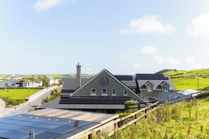 A building with a prominent 'A' logo on the roof, surrounded by green fields and houses.