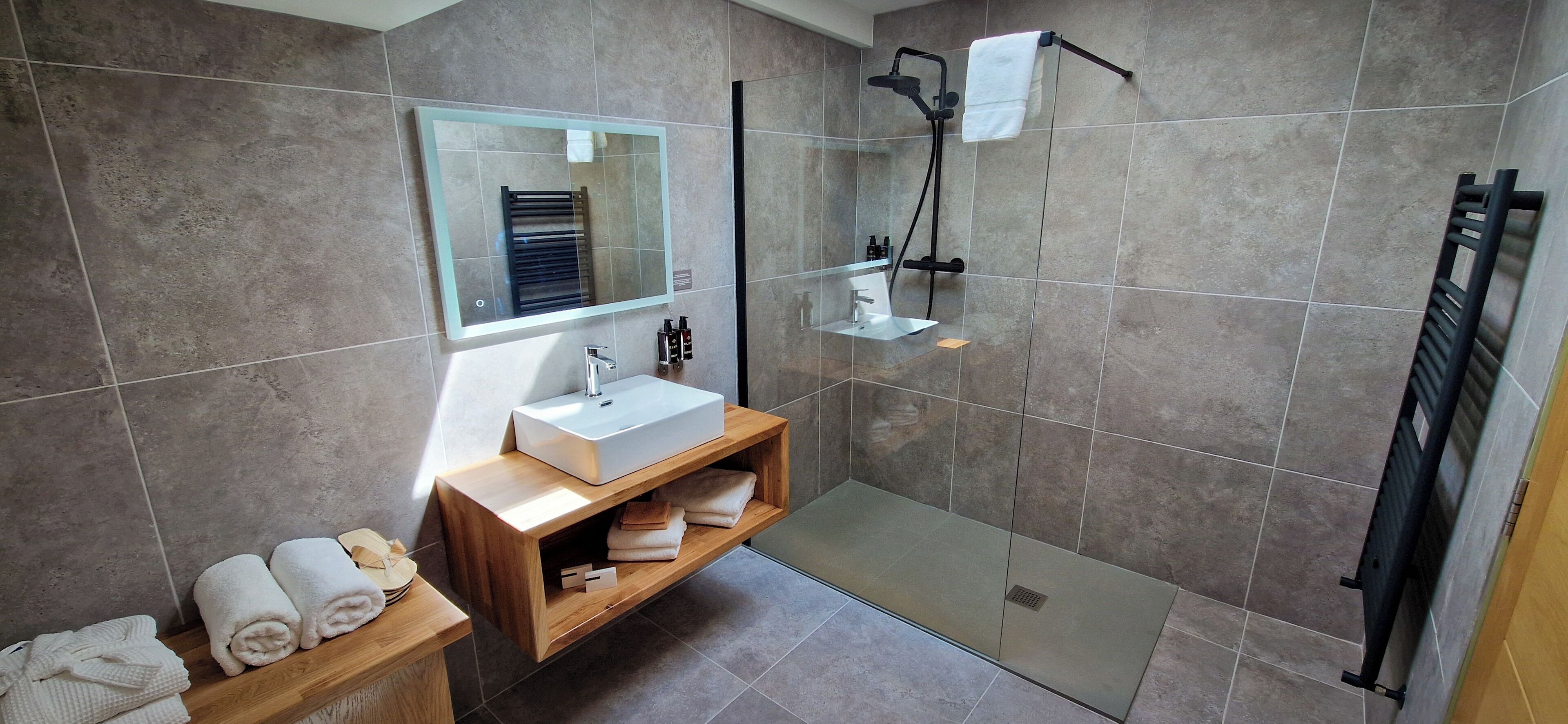 A modern bathroom with a glass-enclosed shower, a wooden vanity with a sink, and a mirror above it.