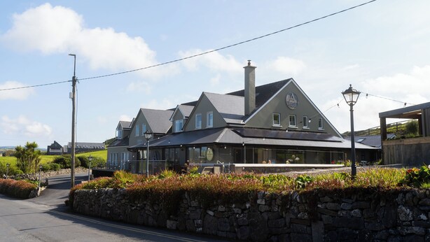 A large, two-story building with a prominent chimney and a covered outdoor seating area.