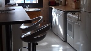 Une cuisine moderne avec un coin repas, des appareils en acier inoxydable et un luminaire suspendu.