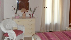 Une chambre à coucher avec un lit, une commode, une chaise et un miroir.