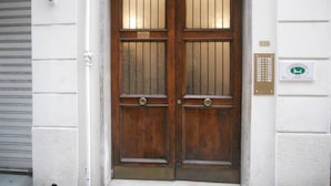 Une porte en bois à deux battants, dotée d’une poignée en métal et d’une plaque numérotée au-dessus.