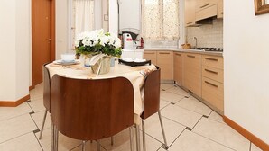 Une cuisine compacte avec un coin repas, comprenant une machine à café, une cuisinière et un évier.