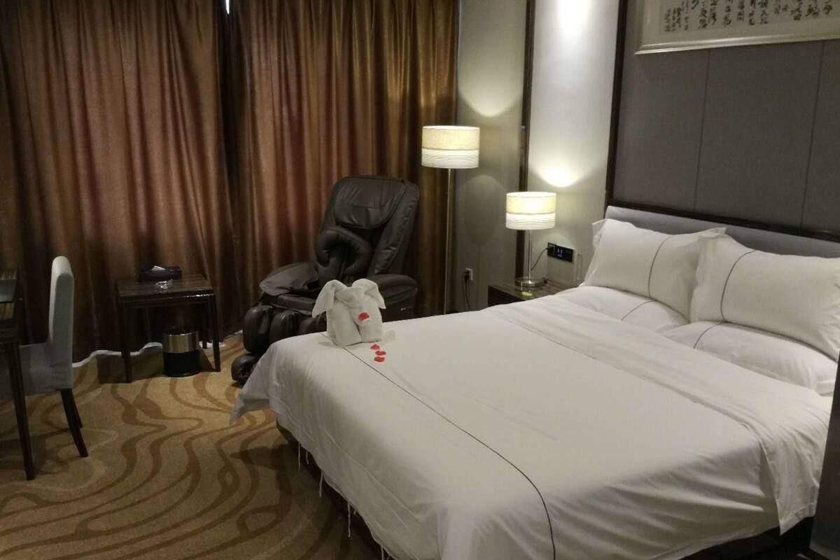 Ein Hotelzimmer mit einem großen Bett, einem Schreibtisch, einem Stuhl und zwei Nachttischlampen.