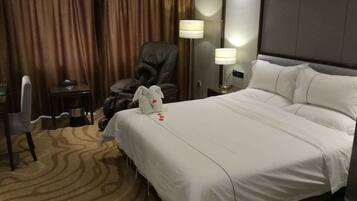 Une chambre d’hôtel avec un grand lit, un bureau, une chaise et deux lampes de chevet.