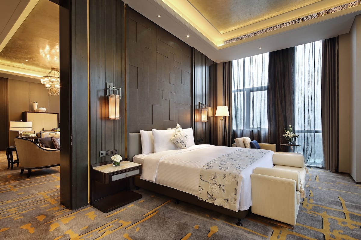 A hotel room with a large bed, a desk, and a view of the outdoors.