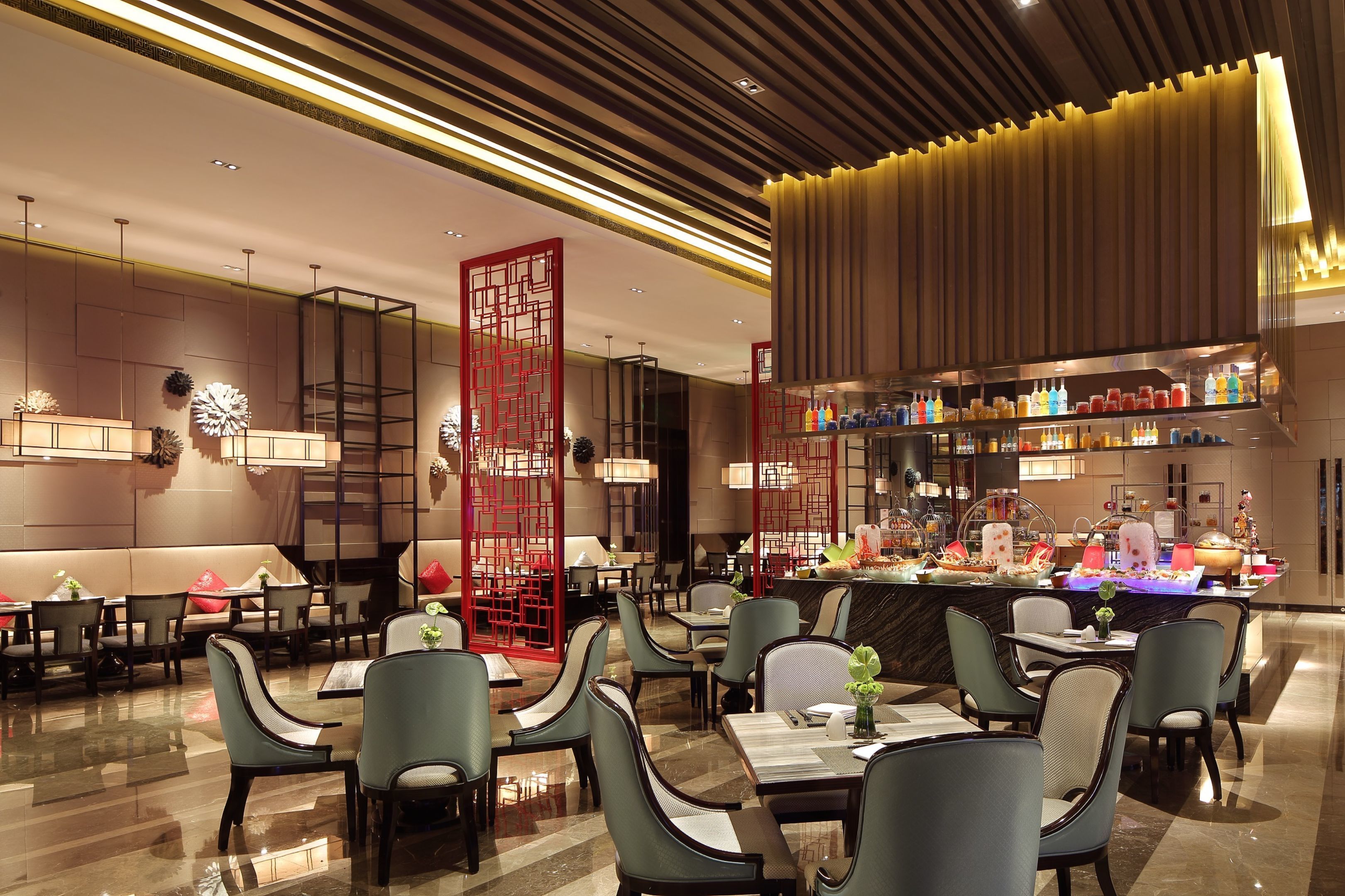 Un restaurante moderno con zona de bar, que ofrece diversas opciones de asientos y un llamativo panel rojo decorativo.