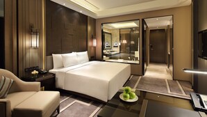 Una moderna camera d'hotel con un letto grande, una zona salotto, una scrivania con una lampada e uno specchio.