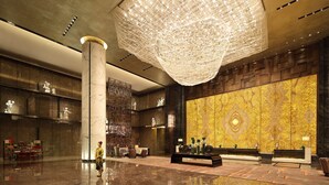 A spacious lobby with a large chandelier, marble columns, and a reception desk. - Wanda Realm Dongying (Dongying)