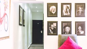 Un pasillo con retratos enmarcados en la pared y una silla con un cojín rojo.
