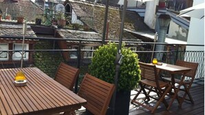 Una terraza de madera con una mesa y sillas, rodeada por una barandilla de metal.