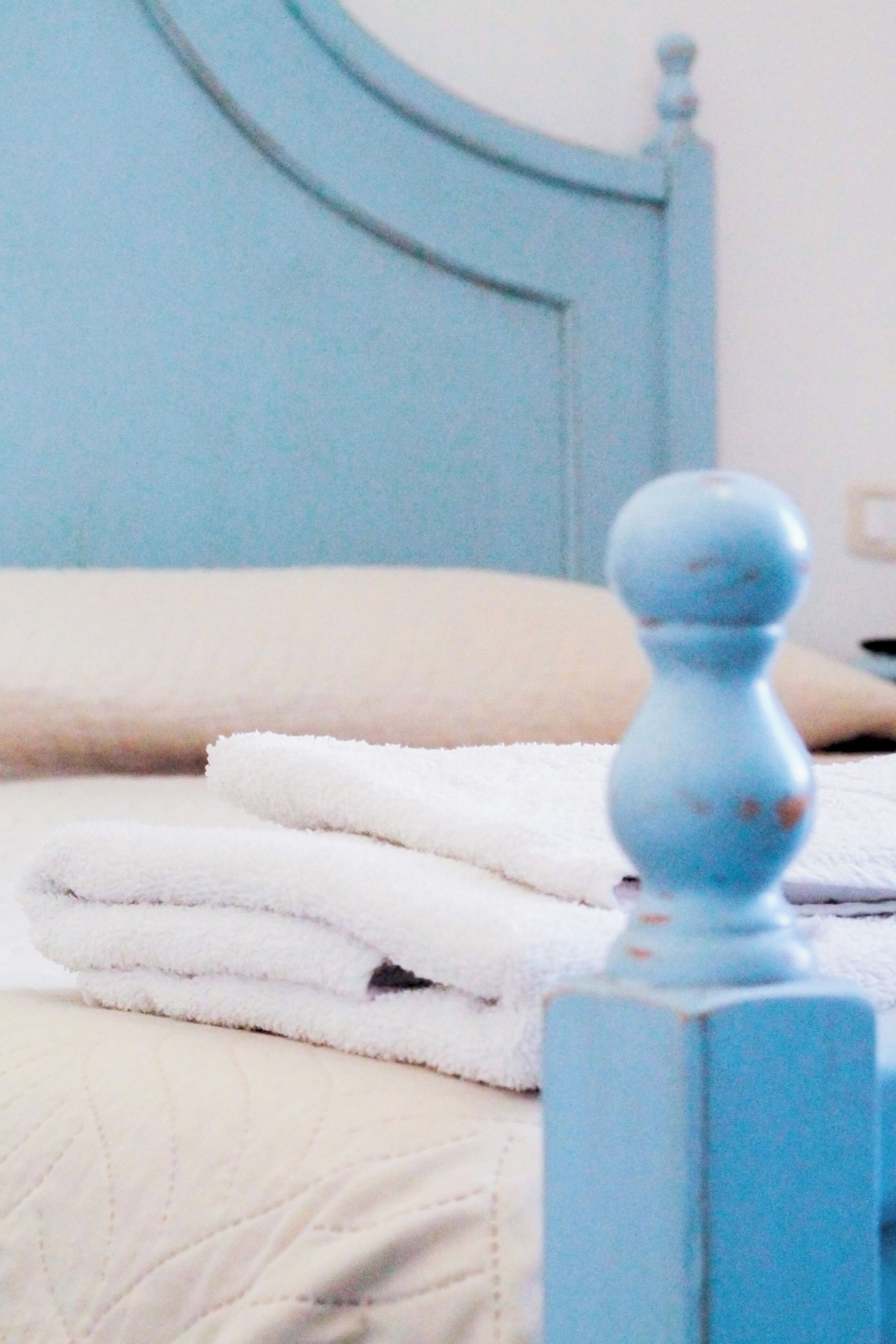 Una cama con cabecera azul y una colcha blanca acolchada.