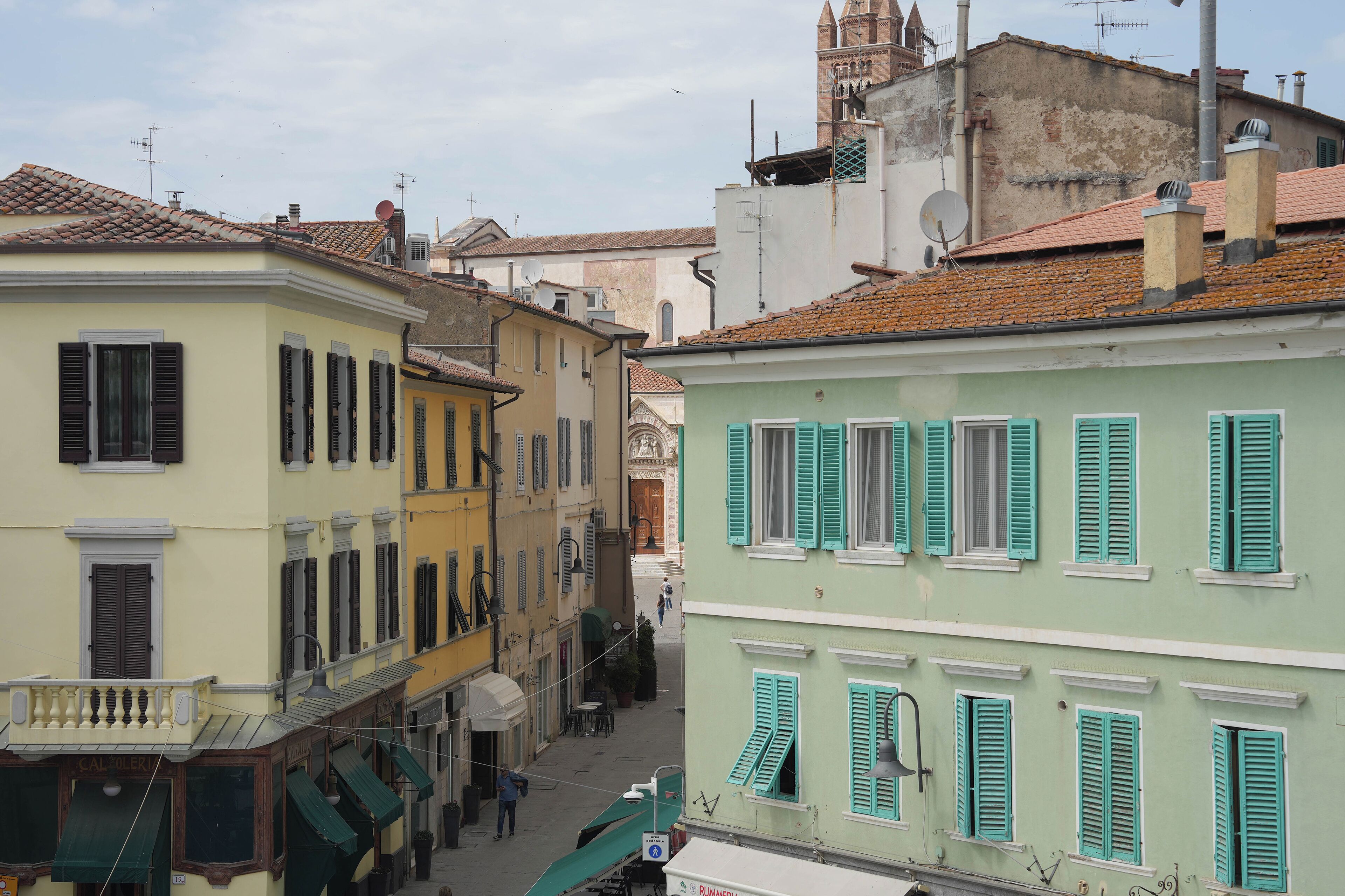 A narrow street with buildings featuring traditional architecture and shutters.