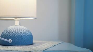 A blue textured lamp on a bedside table with a lace doily.