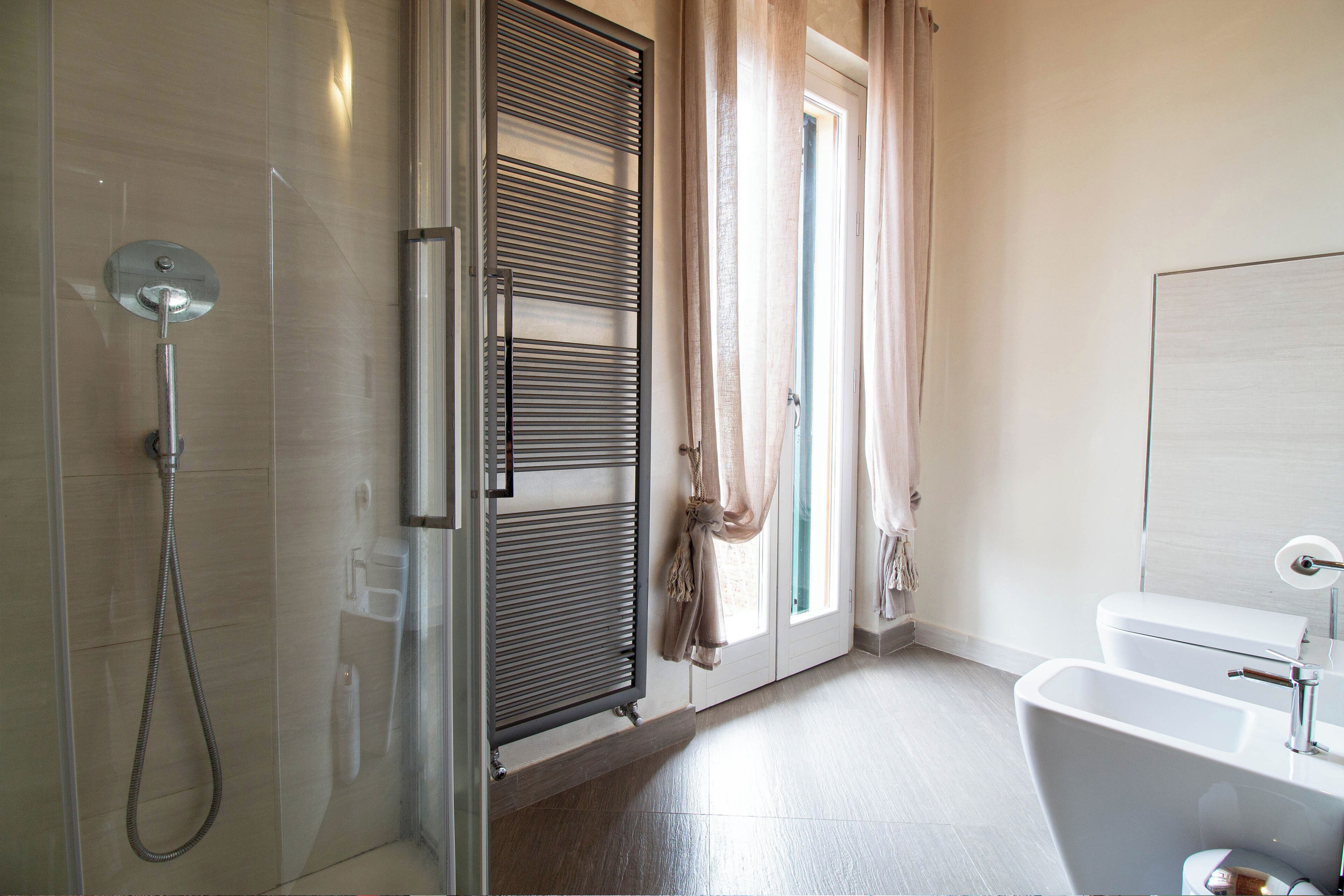 Un baño moderno con cabina de ducha de vidrio, una bañera independiente y un inodoro.
