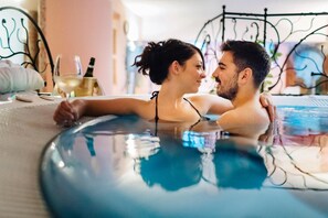 A couple in a hot tub with a laptop and a bottle of wine on the side. - Albergo La Montanina (Alleghe)