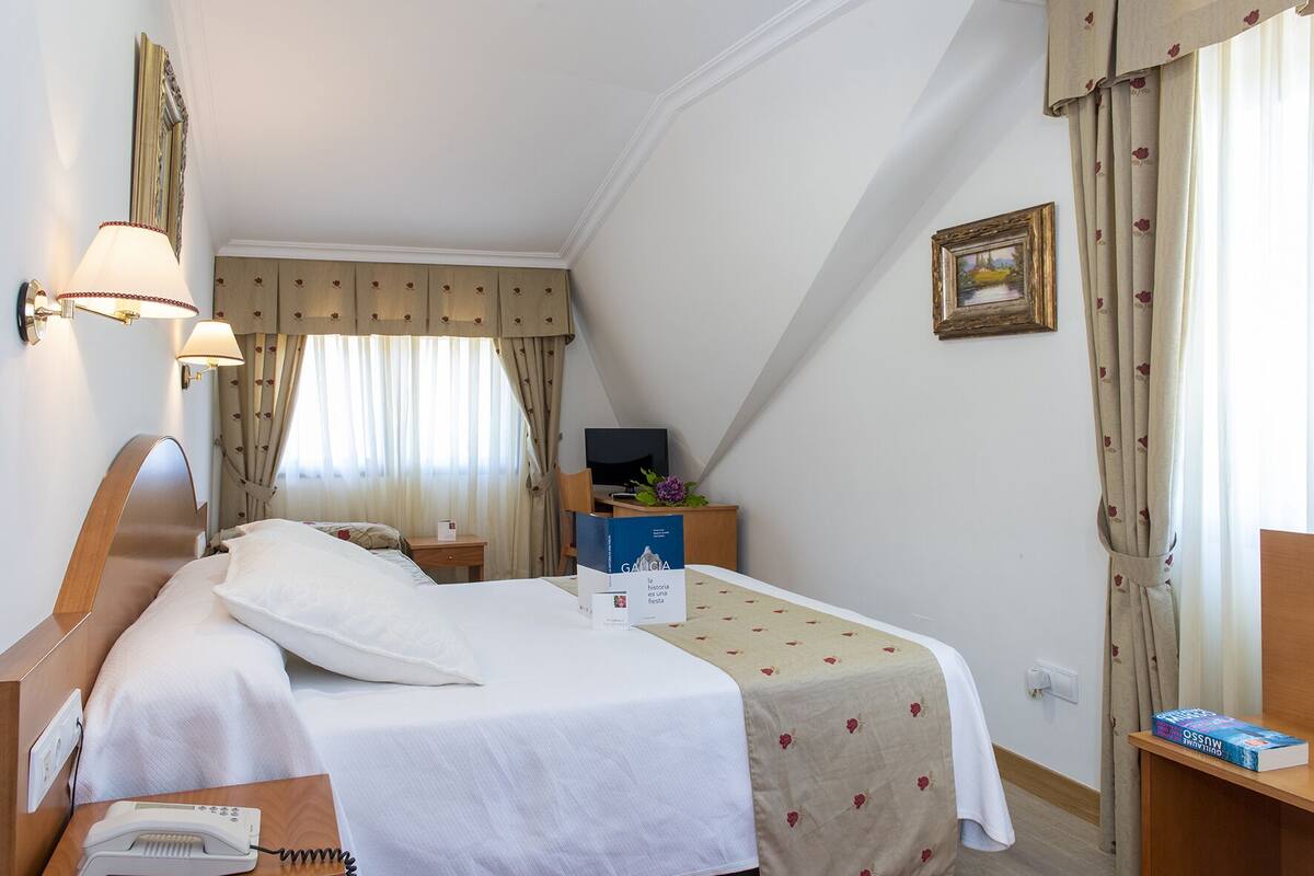 Une chambre d’hôtel équipée d’un lit, d’une table de chevet, d’une lampe et d’un bureau avec un ordinateur.