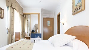 Habitación de hotel con una cama grande, un escritorio con computadora, un armario y una puerta con espejo.