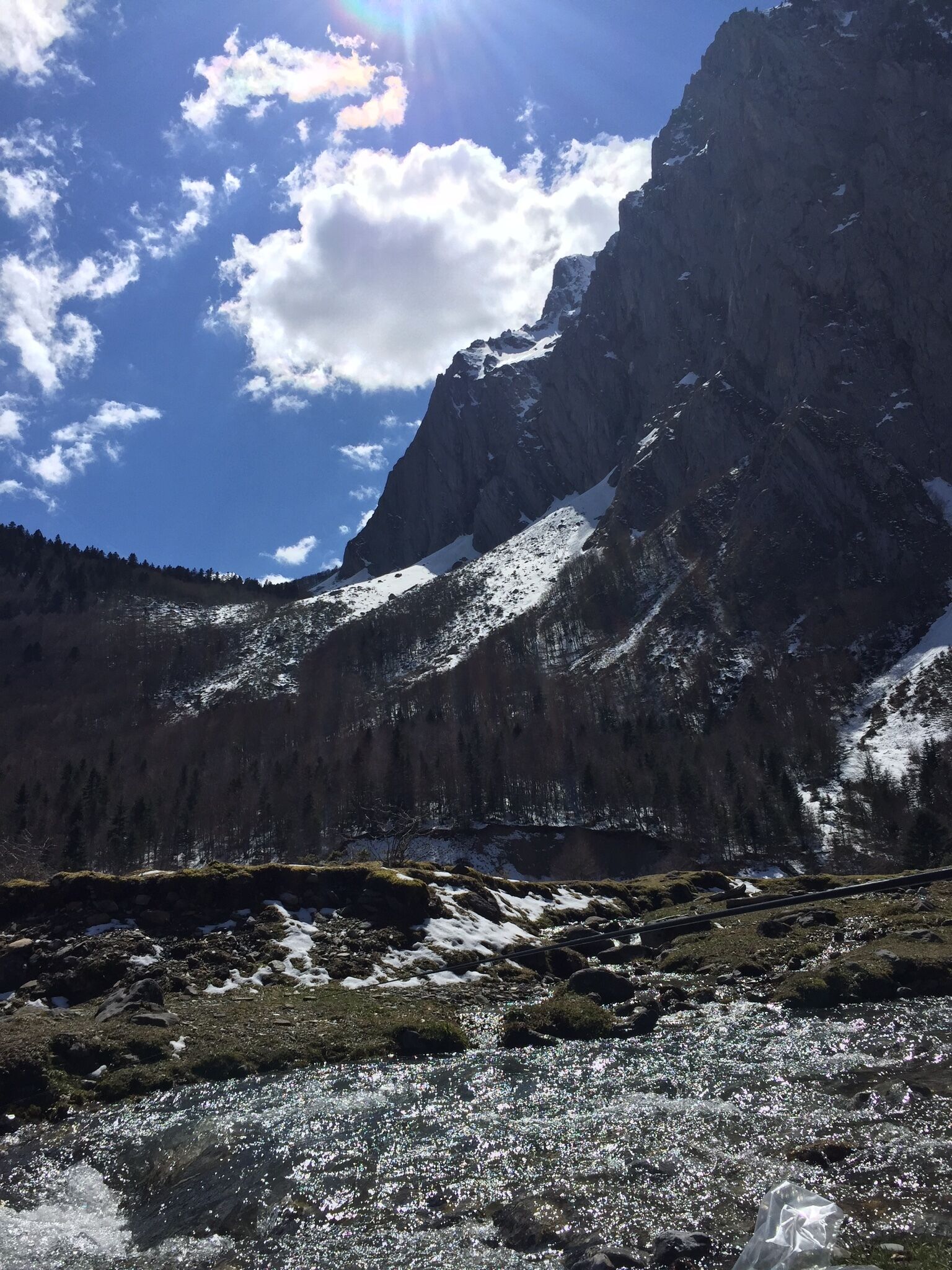 A mountainous landscape with a clear sky, snow-covered peaks, and a river in the foreground.