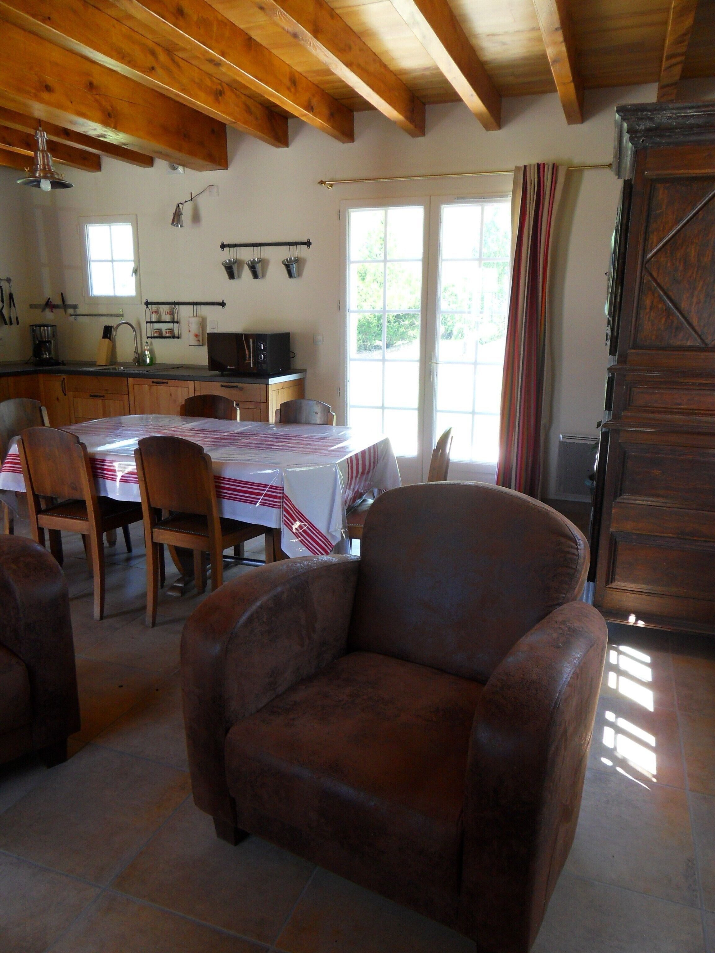 Une cuisine rustique avec des poutres en bois, une table à manger avec des chaises et un grand buffet en bois.