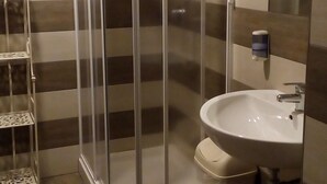 Et badeværelse med brusekabine, vask og toilet.