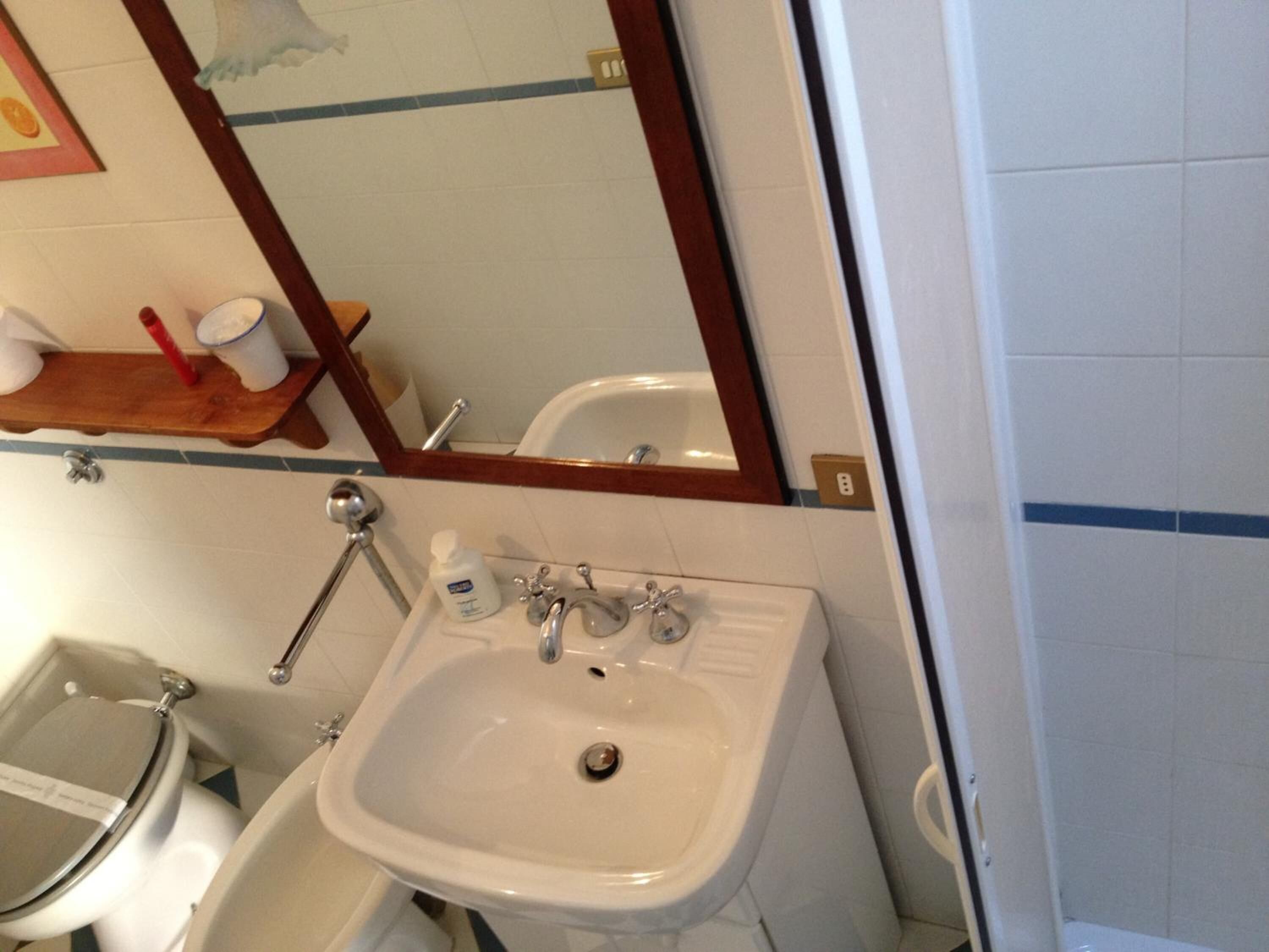 A bathroom with a white sink, a mirror, and a toilet.