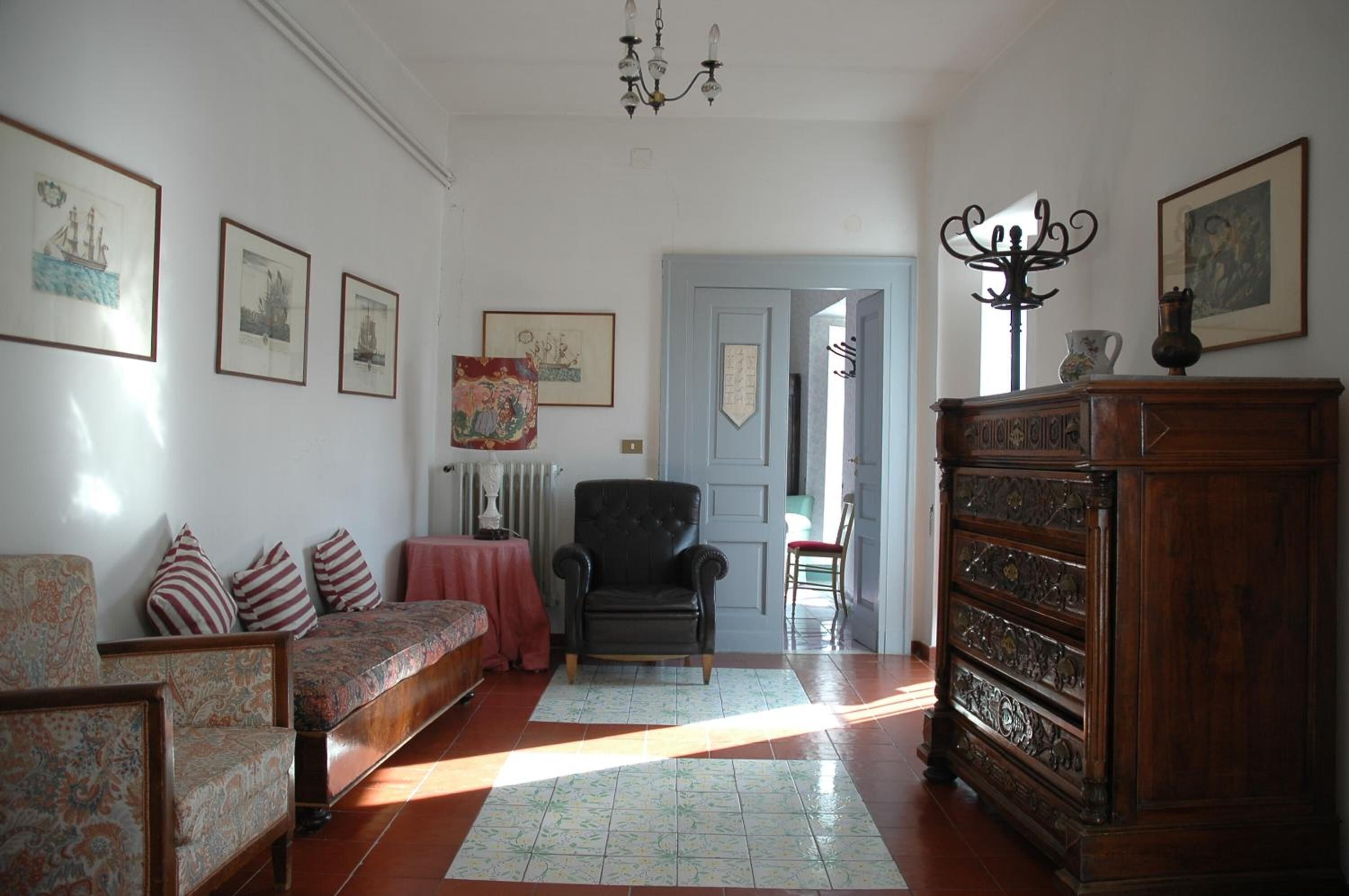 Una habitación con sofá, sillones, un mueble de madera y obras de arte enmarcadas en las paredes.