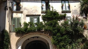 An arched entrance to a building with a cobblestone path leading up to it, surrounded by lush greenery and potted plants. - Agriturismo Mustilli (Sant'Agata de'Goti)