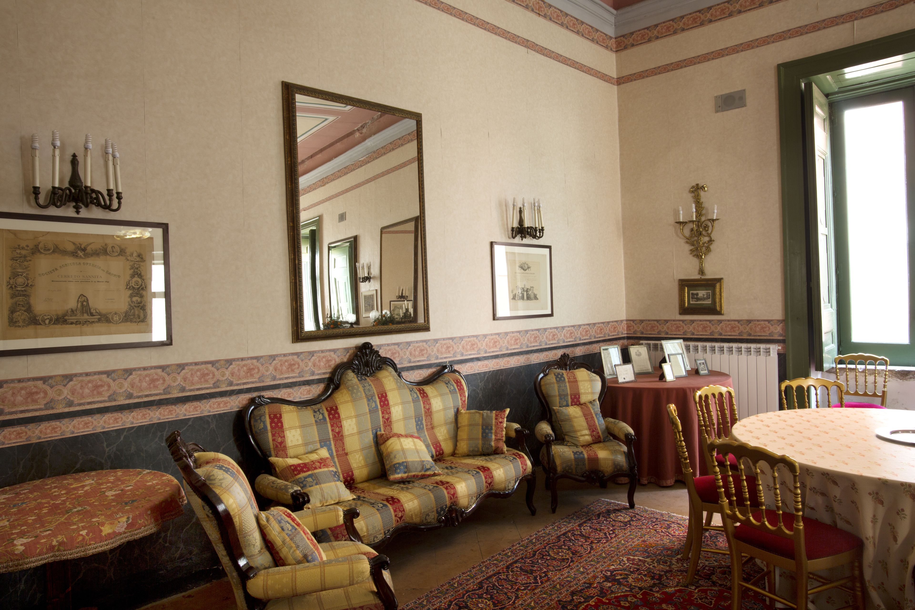 Una habitación con un conjunto de sofá, sillas, una mesa y un espejo grande.