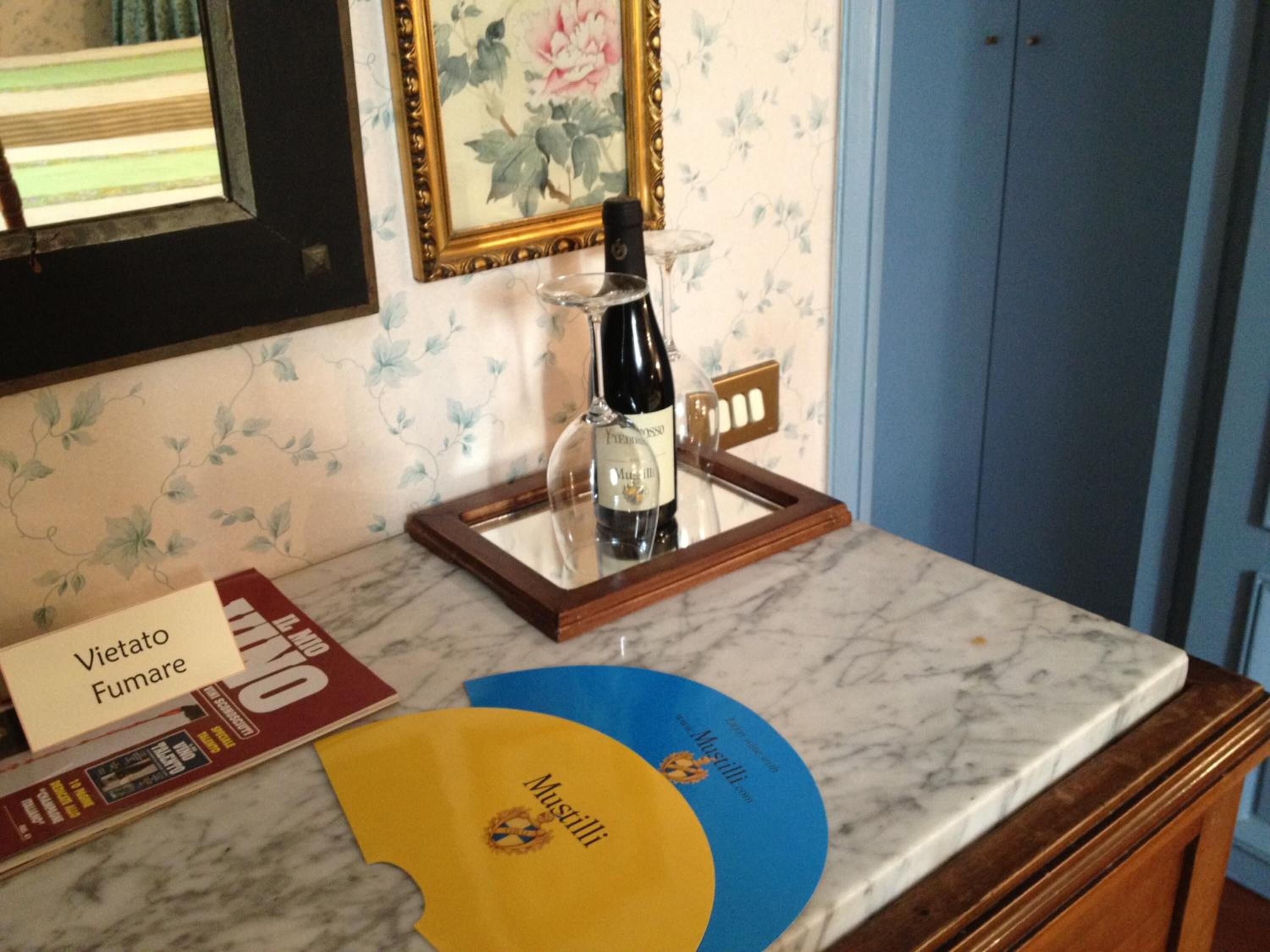 Un comptoir en marbre avec une bouteille de vin, un cadre photo et un présentoir à menus.