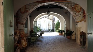 An arched corridor with a rustic stone floor, a wooden cart, and a table with chairs. - Agriturismo Mustilli (Sant'Agata de'Goti)
