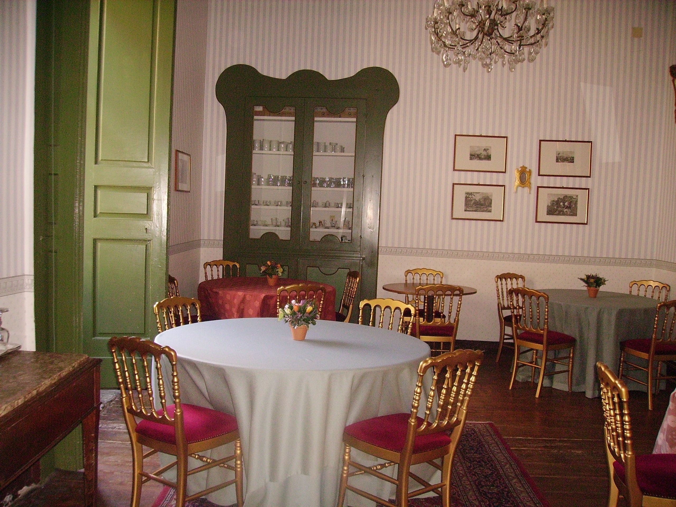 Un comedor con una mesa redonda, sillas, una araña y cuadros en la pared.
