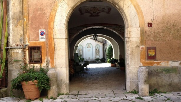 An arched entrance to a building with a cobblestone pathway leading inside. - Agriturismo Mustilli (Sant'Agata de'Goti)
