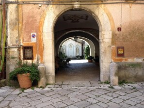 An arched entrance to a building with a cobblestone pathway leading inside. - Agriturismo Mustilli (Sant'Agata de'Goti)