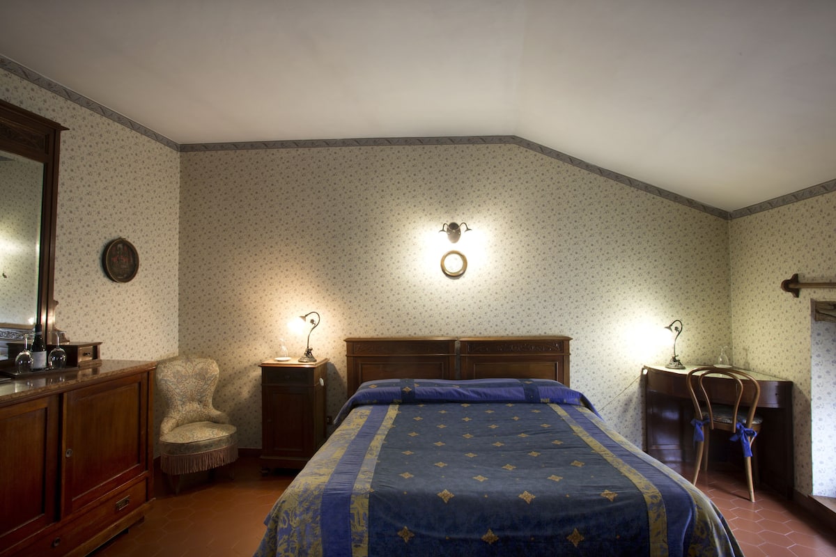 Une chambre à coucher avec un lit, une chaise, un bureau et un miroir.