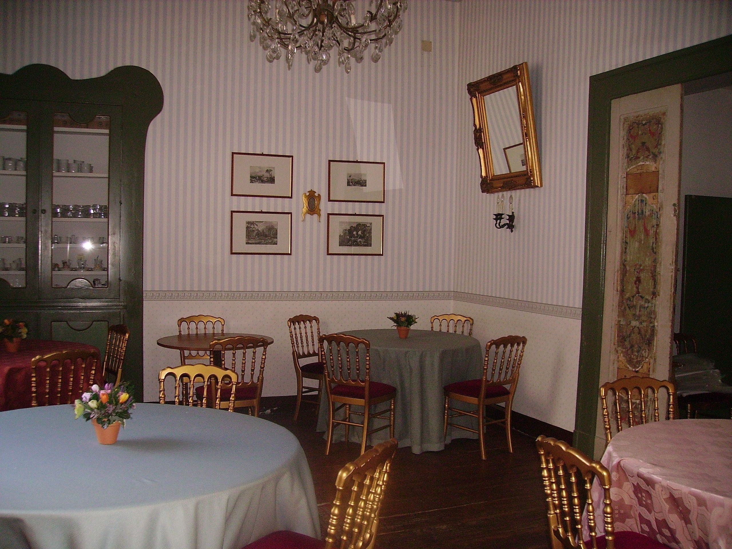 A dining room with round tables, chairs, and framed pictures on the wall.
