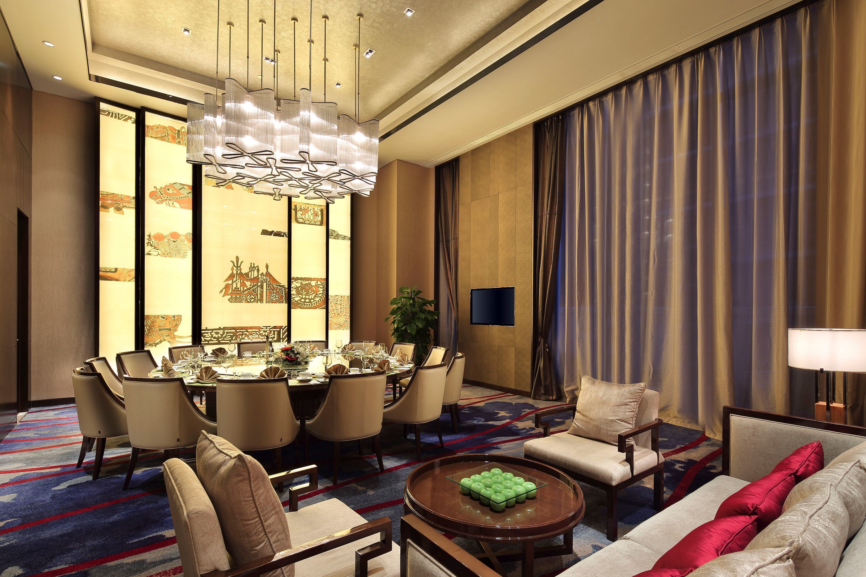A spacious hotel room with a dining area, a sofa, a coffee table, and a TV.