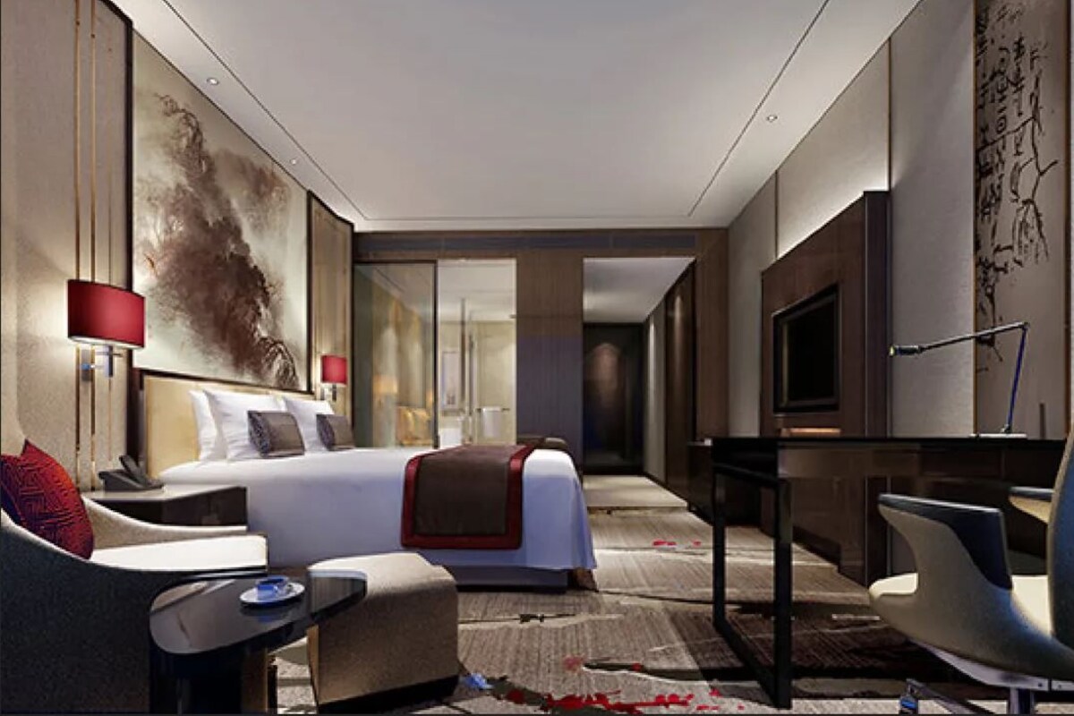 A modern hotel room with a large bed, a desk, a chair, and a television.