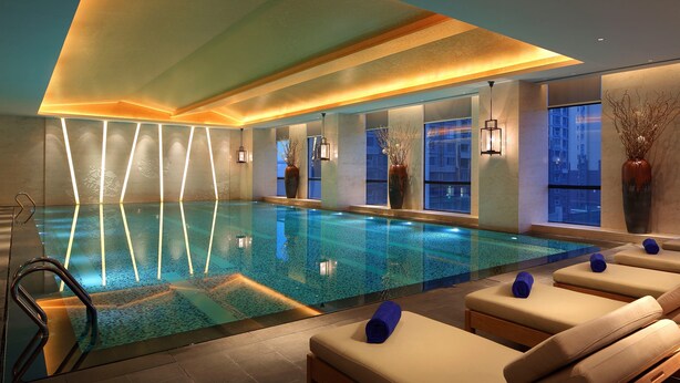 A modern indoor swimming pool with clear water, lounge chairs, and ambient lighting. - Wanda Realm Anyang (Anyang)