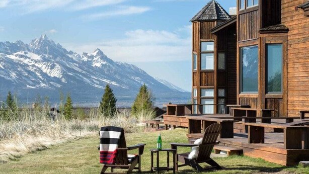 A wooden cabin with a deck, two chairs, and a table. - Outpost: Spirit Dance 3110 - Summer Pool Access! (Jackson)