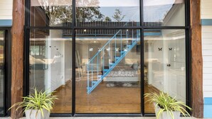 Ein moderner Hauseingang mit Glastüren, einer blauen Treppe und Topfpflanzen.