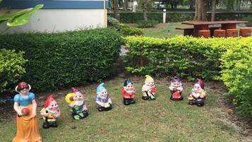 Un jardín con una hilera de estatuas de gnomos y una estatua de Blancanieves.