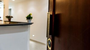 A wooden door with a brass handle and a keyhole, leading to a reception area with a counter and potted plants. - Mr. Charlie Brown (Rome)