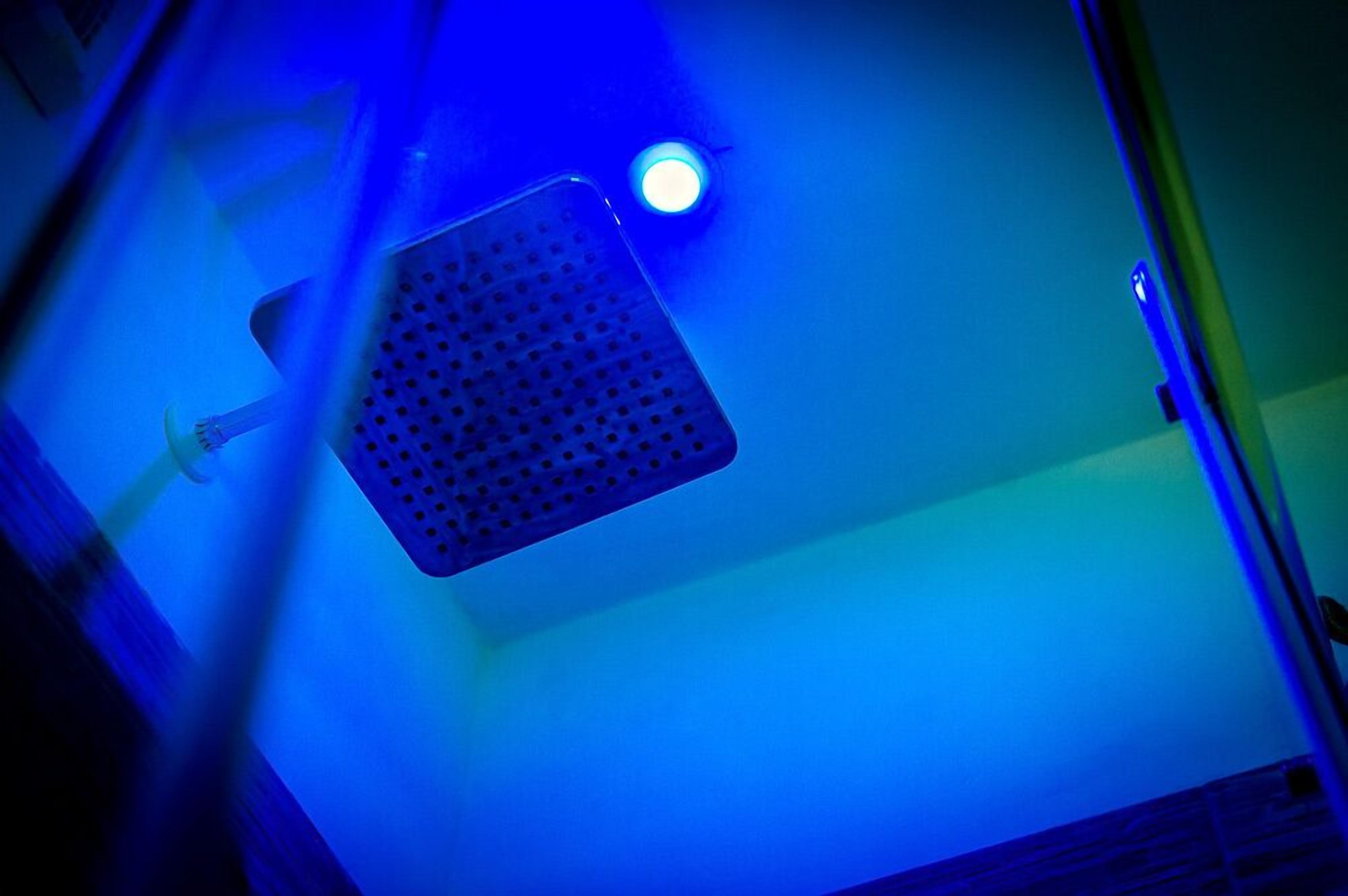 A ceiling with a blue light fixture and a ventilation grille.