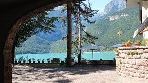 Um pátio de pedra com área de estar ao ar livre, com vista para um lago e montanhas.