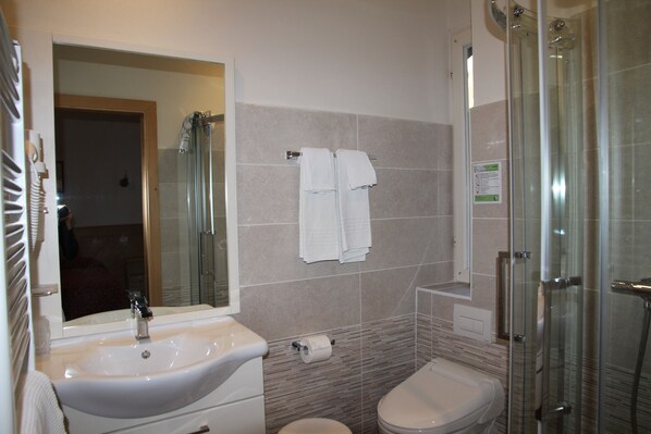 Een badkamer met wastafel, toilet en glazen douchecabine.