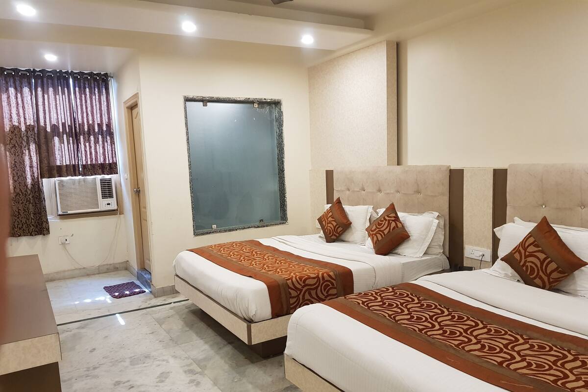 Une chambre d’hôtel avec deux lits, un grand miroir, un appareil de climatisation et un sol en marbre.