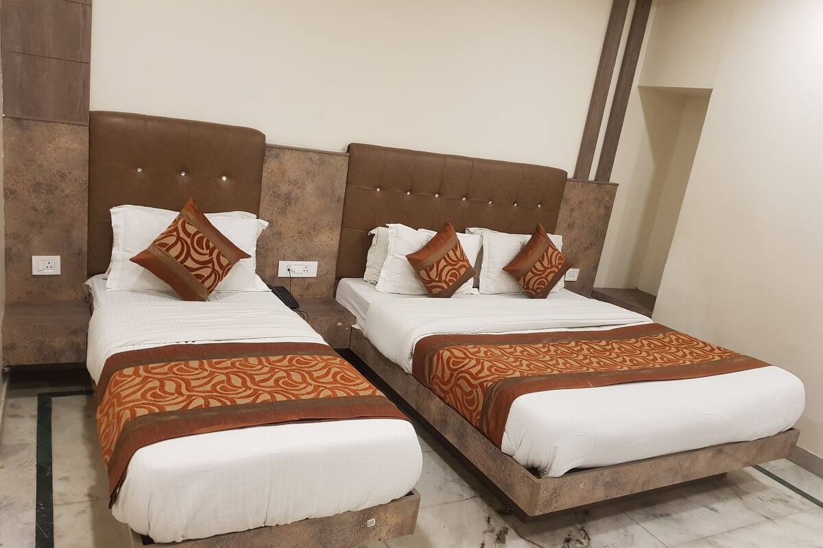 Deux lits jumeaux avec des têtes de lit marron et des couvre-lits à motifs, du linge de lit blanc et des coussins décoratifs marron assortis.