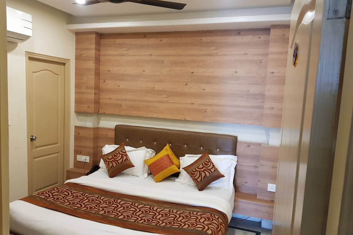 Un lit bien fait, avec une couvre-lit à motifs, une tête de lit en bois et des coussins décoratifs.