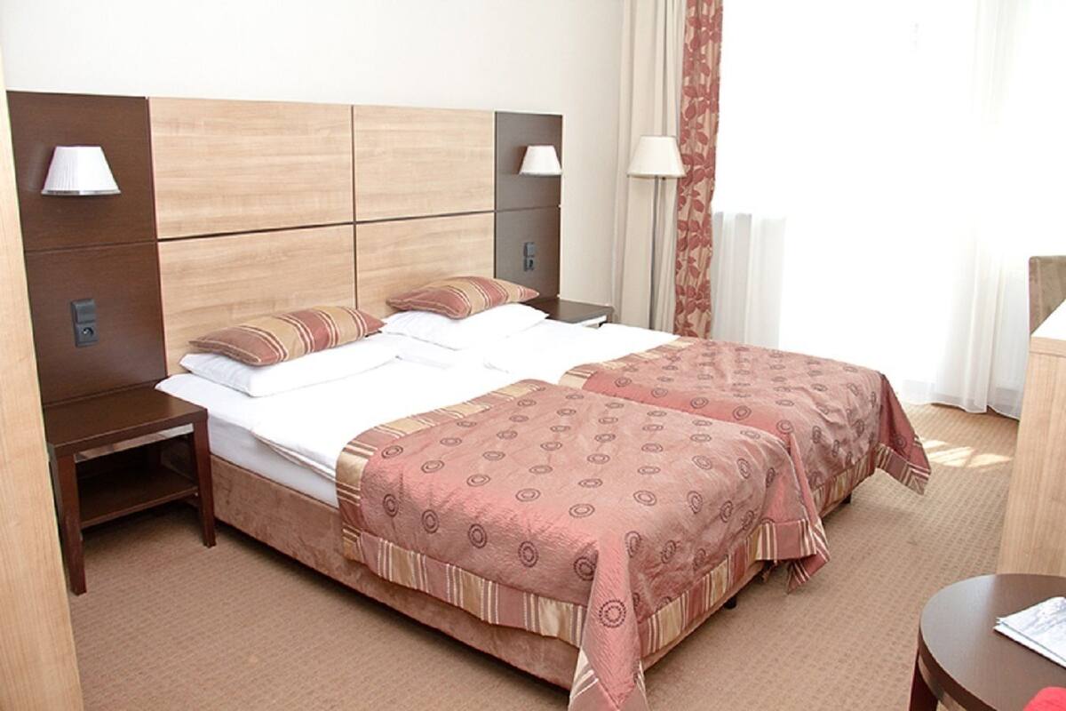 A double bed with a wooden headboard, two bedside tables with lamps, and a patterned bedspread.